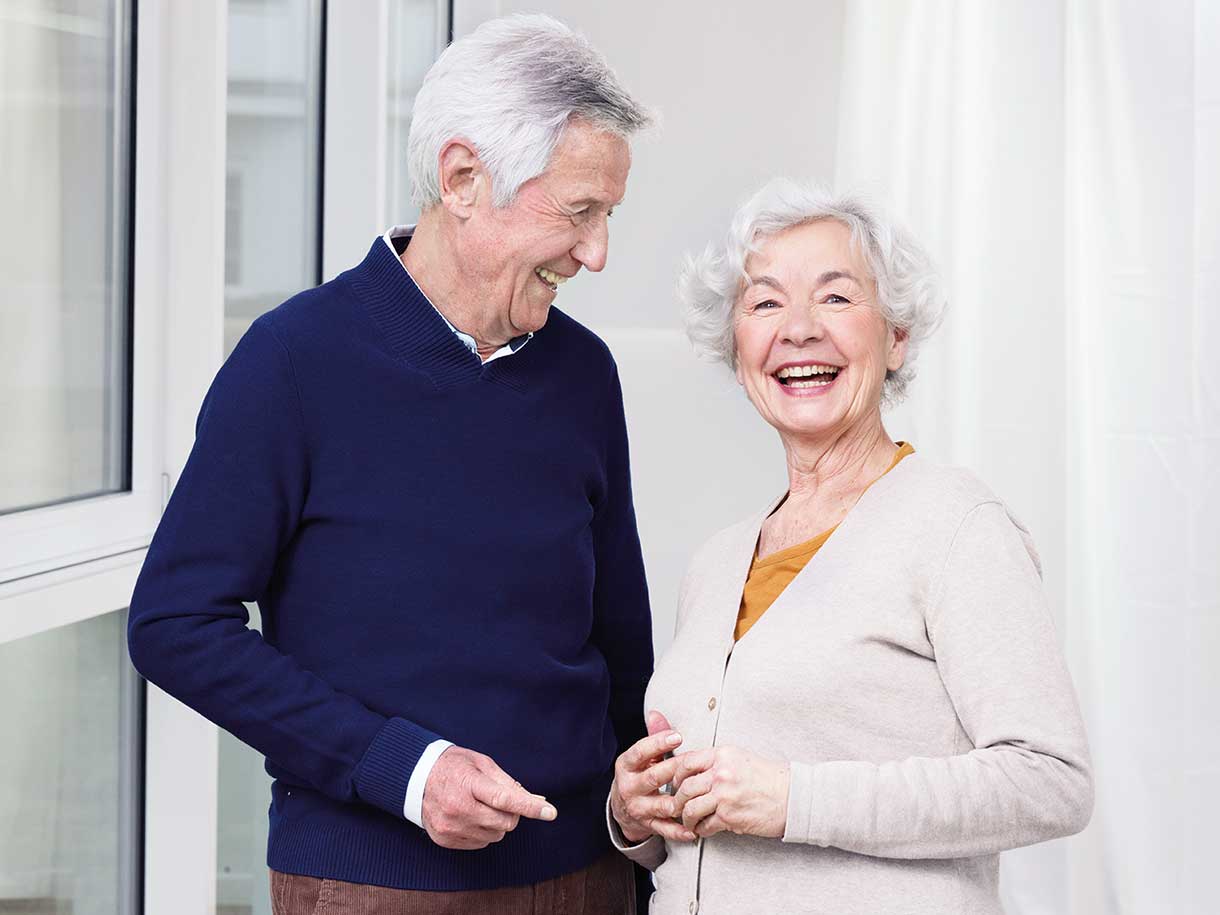 An older man and older woman standing together, smiling